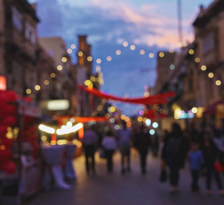 blurred background of town street decorated with christmas lights and people walking fair